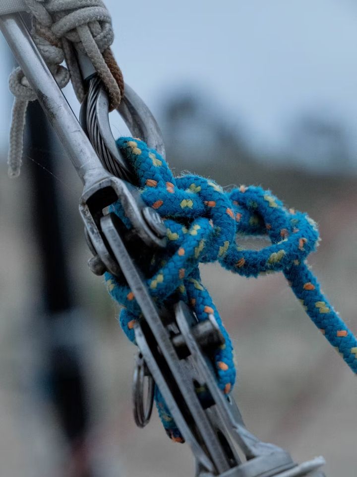 A blue rope knotted through a stainless-steel shackle