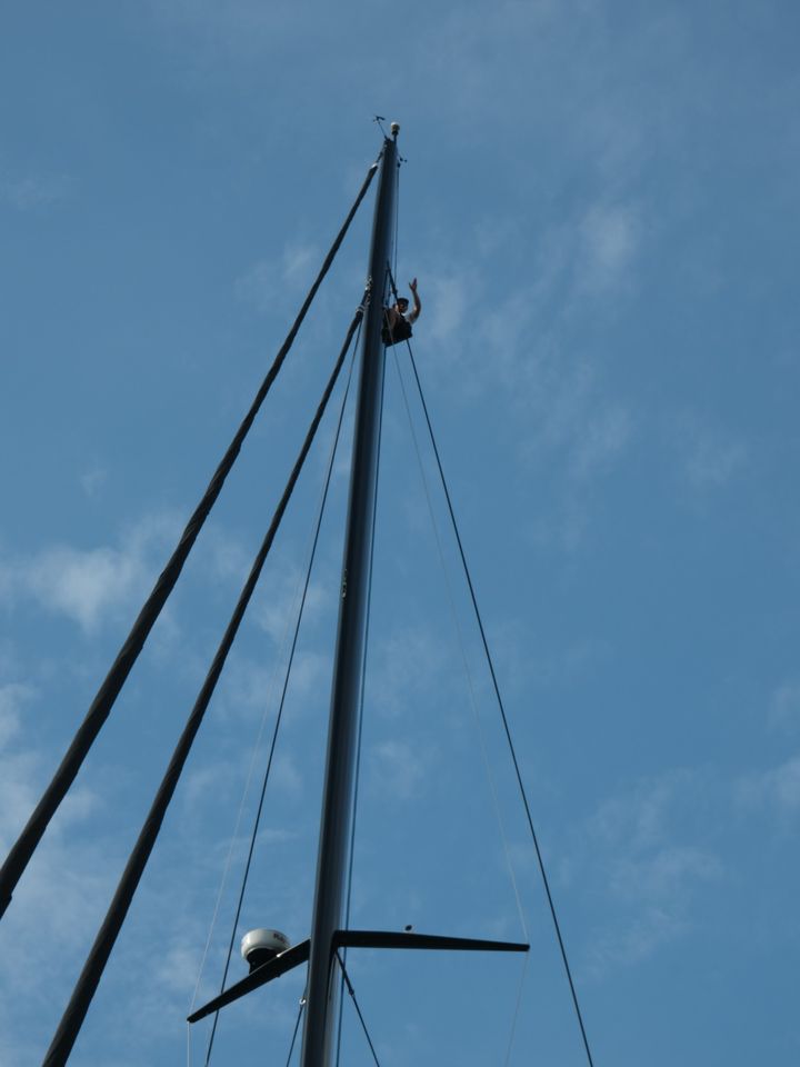 A crew member waving from the rig, high up the mast